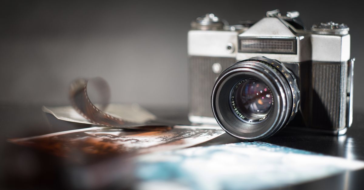 A vintage camera with a blurred film strip and photographs, creating a nostalgic feel.